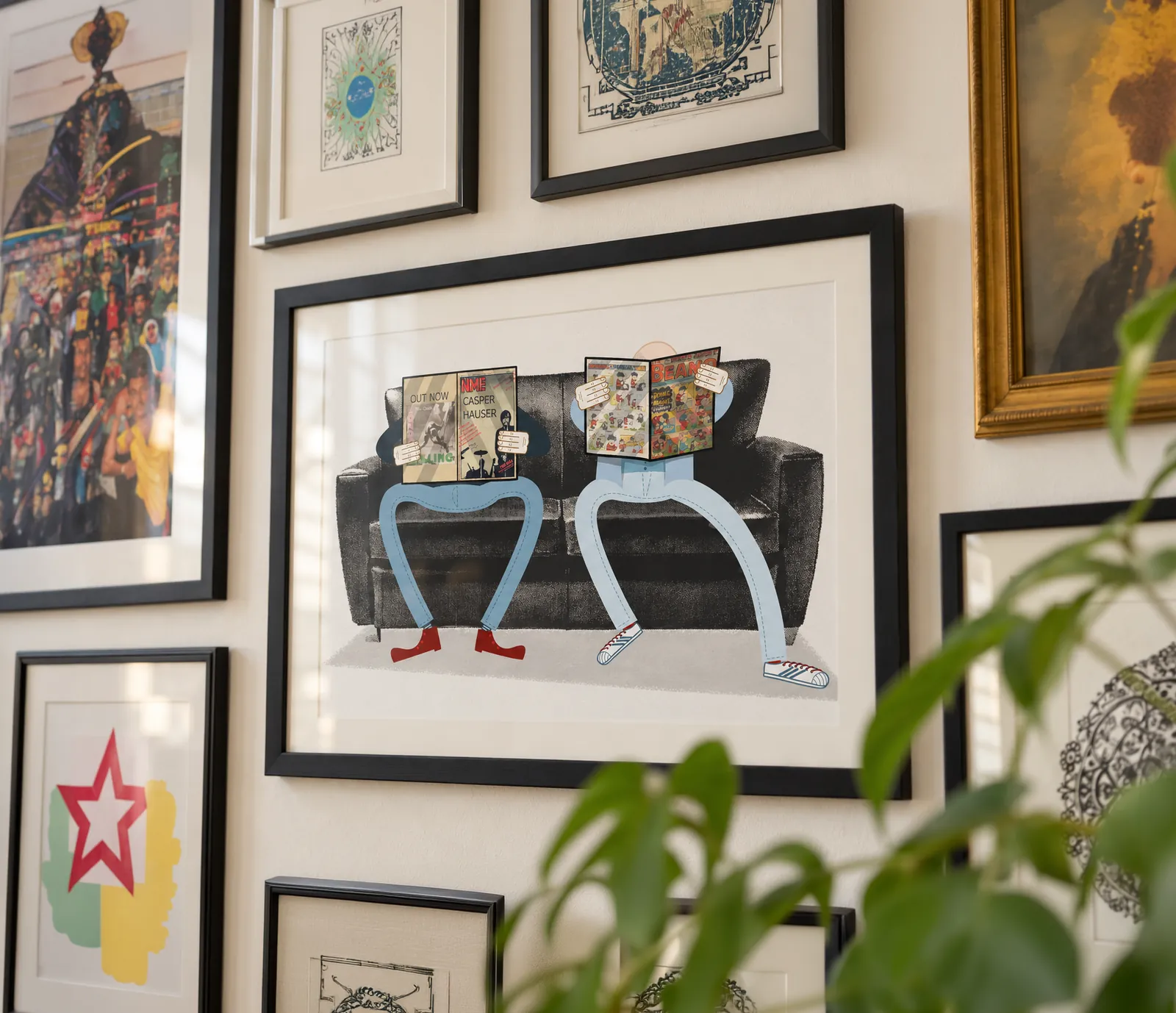 Framed illustration of Dan Taylor and Andy Watkins sitting on a sofa, reading magazines, hanging on a gallery wall